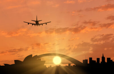 A photo of dawning breaking over Sydney Opera House and Sydney Harbour Bridge with an airplane coming into land.